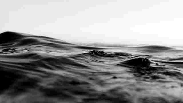 Black-and-white close-up of dark water ripples under a pale horizon