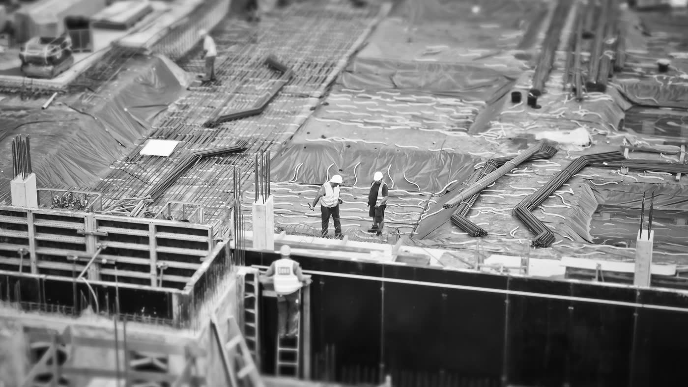 Black-and-white overhead view of a construction site with rebar grids and formwork