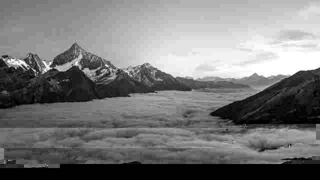 Black-and-white mountain peaks rising above a thick sea of valley fog