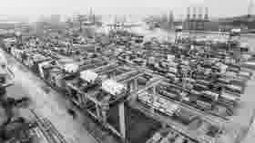 Black-and-white aerial view of a container terminal with gantry cranes and stacked containers