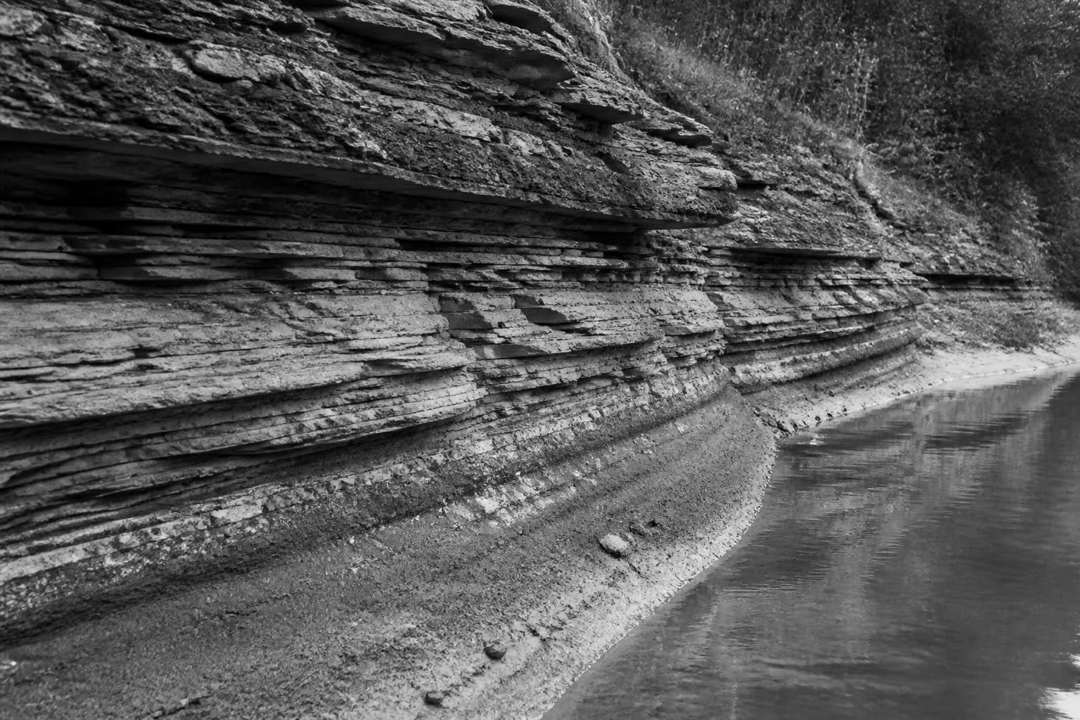 Black-and-white layered stone riverbank standing in for a model under the surface